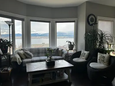 a living room with a couch and a table and windows at Casa Grande Lakeview House in West Kelowna