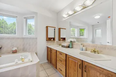 a white bathroom with two sinks and a tub at Casa Grande Lakeview House in West Kelowna