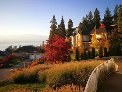 a house on a hill with a white fence at Casa Grande Lakeview House in West Kelowna