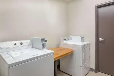 a laundry room with a sink and a washer and dryer at Super 8 by Wyndham Innisfail in Innisfail