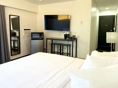 a bedroom with a bed and a kitchen with a television at The Spot in Nanaimo