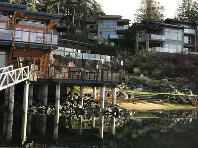 a building next to a body of water with houses at Painted Boat Resort Spa and Marina in Madeira Park