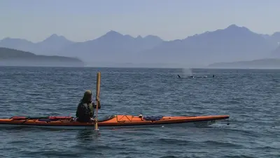 a man sitting in a kayak in the water at Painted Boat Resort Spa and Marina in Madeira Park