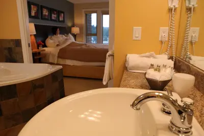 a bathroom with a sink and a mirror and a bed at Painted Boat Resort Spa and Marina in Madeira Park