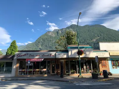 a store on a street with a mountain in the background at City Centre Motel older building in Hope
