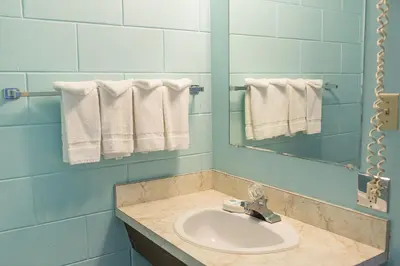 a bathroom with a sink and a mirror and towels at City Centre Motel older building in Hope