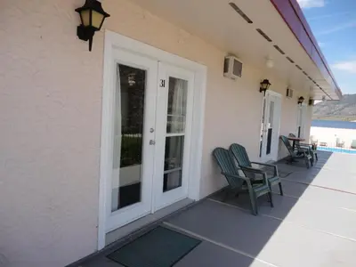 a patio with two chairs and a table on a house at Falcon Resort in Osoyoos