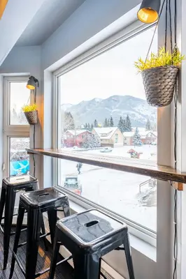 a room with two stools and a large window at Samesun Banff Hostel in Banff