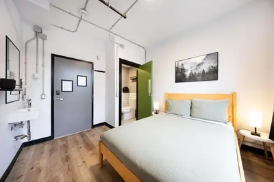 a bedroom with a large bed and a bathroom at Samesun Vancouver in Vancouver