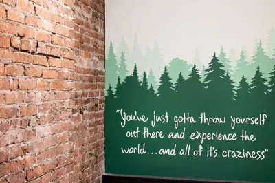 a sign on a brick wall with a forest of trees at Samesun Vancouver in Vancouver