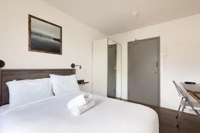 a bedroom with a white bed and a desk at HI Kelowna Hostel in Kelowna