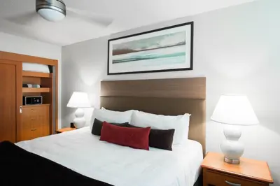 a bedroom with a large white bed with two lamps at West Coast Suites at UBC in Vancouver
