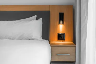 a bed with a white pillow and a night stand at Gage Suites at UBC in Vancouver