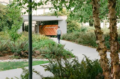 a man walking down a sidewalk in a garden at Gage Suites at UBC in Vancouver