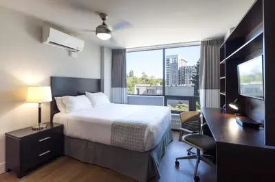 a hotel room with a bed and a desk and a window at Gage Suites at UBC in Vancouver