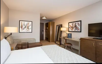 a hotel room with a bed and a desk and a television at Pomeroy Inn & Suites Prince George in Prince George
