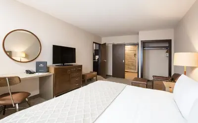a hotel room with a bed and a desk and a mirror at Pomeroy Inn & Suites Prince George in Prince George