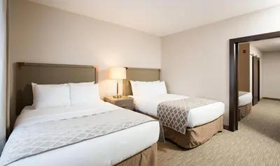 a hotel room with two beds and a lamp at Pomeroy Inn & Suites Prince George in Prince George