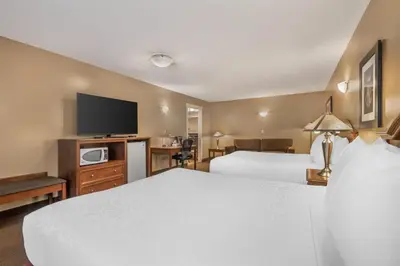 a hotel room with two beds and a flat screen tv at Best Western Sicamous Inn in Sicamous