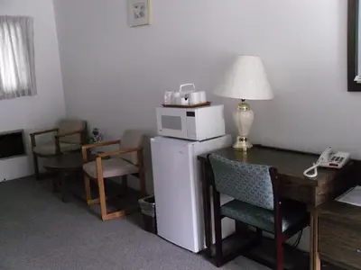 a room with a desk with a microwave on top of a refrigerator at Canyon Alpine Motel in Boston Bar