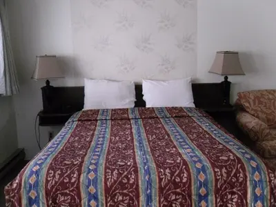 a bed in a hotel room with two lamps at Canyon Alpine Motel in Boston Bar