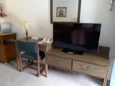 a room with a desk with a television and a chair at Canyon Alpine Motel in Boston Bar