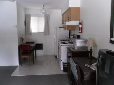 a small kitchen with a table and a refrigerator at Canyon Alpine Motel in Boston Bar
