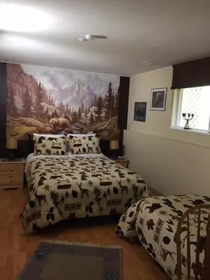 a bedroom with two beds and a painting on the wall at Silvern Lake Trail Bed and Breakfast in Smithers