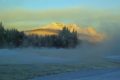 a mountain in the distance with fog in front of trees at Silvern Lake Trail Bed and Breakfast in Smithers