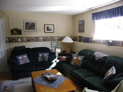 a living room with two green couches and a table at Silvern Lake Trail Bed and Breakfast in Smithers