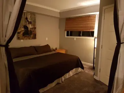 a bedroom with a black bed and a window at Riverbend Guest House in Chilliwack