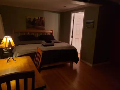 a bedroom with a bed and a table with a lamp at Riverbend Guest House in Chilliwack