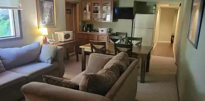 a living room with two couches and a table and a kitchen at Riverbend Guest House in Chilliwack