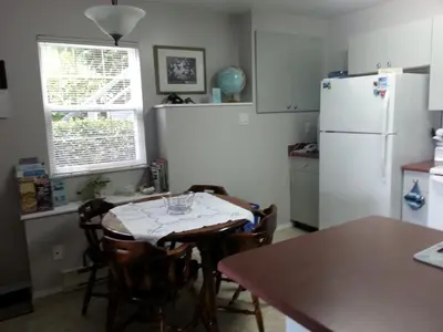 a kitchen with a table and a white refrigerator at Hammond Bay Oceanside Guesthouse in Nanaimo