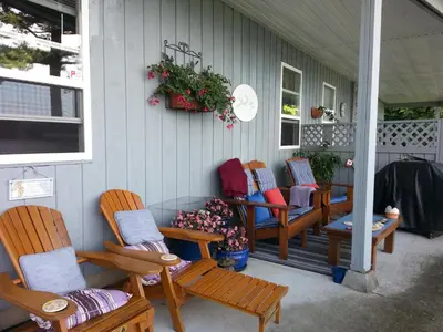 a group of chairs sitting on the front porch of a house at Hammond Bay Oceanside Guesthouse in Nanaimo