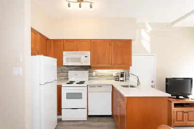 a kitchen with white appliances and wooden cabinets at Alpenglow Lodge by MVA in Whistler