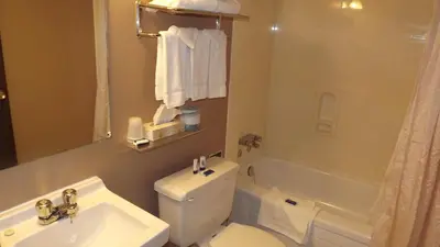 a bathroom with a sink and a toilet and a tub at The Pacific Inn in Prince Rupert