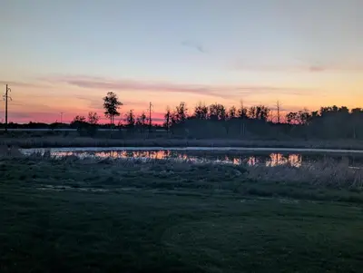 a sunset over a pond in a field at The Ranch Highway 55 in Debden