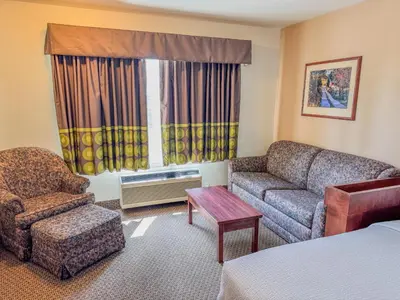 a hotel room with a couch and a chair at Super 8 by Wyndham High River AB in High River