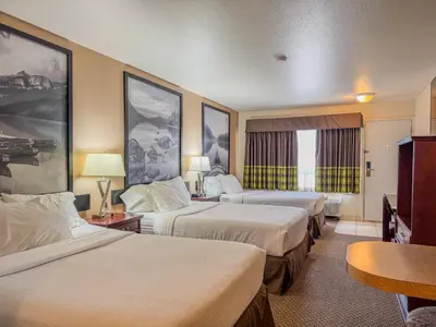 a hotel room with three beds and a table at Super 8 by Wyndham High River AB in High River