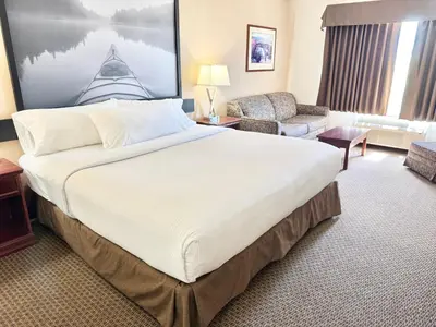 a hotel room with a large bed and a chair at Super 8 by Wyndham High River AB in High River