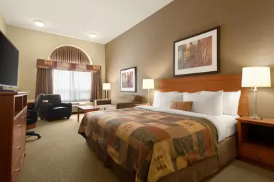 a hotel room with a large bed and a television at Ramada by Wyndham Drayton Valley in Drayton Valley
