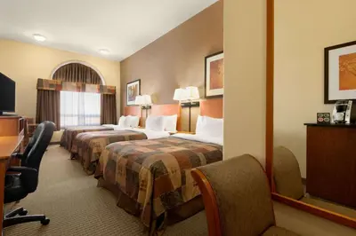 a hotel room with two beds and a desk at Ramada by Wyndham Drayton Valley in Drayton Valley