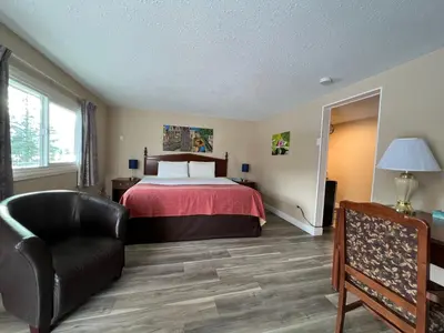 a hotel room with a bed and a chair at Villa Motel in Nelson