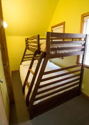 two bunk beds in a room with a yellow wall at Reef Point Cottages in Ucluelet