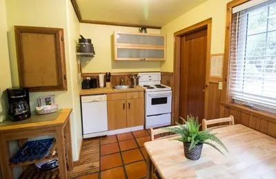 a kitchen with a table and a white stove top oven at Reef Point Cottages in Ucluelet