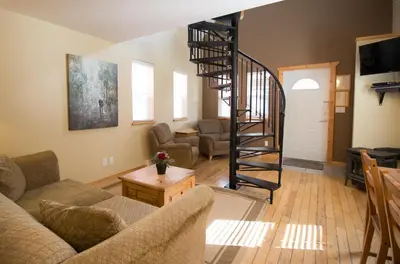 a living room with a spiral staircase in a house at Reef Point Cottages in Ucluelet