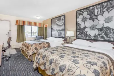 a hotel room with two beds and a desk at Super 8 by Wyndham Stettler in Stettler