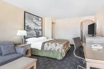 a small hotel room with a bed and a couch at Super 8 by Wyndham Stettler in Stettler