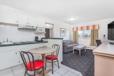 a kitchen and living room with a table and chairs at Super 8 by Wyndham Stettler in Stettler